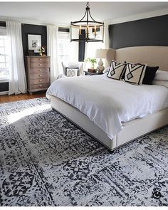 a bed room with a neatly made bed and a large rug on the floor next to a window