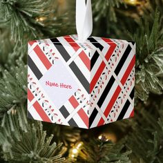 an ornament hanging from a christmas tree decorated with red, black and white stripes