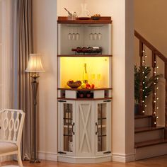 a lighted display cabinet in the corner of a living room with stairs leading up to it