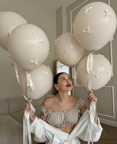 a woman is holding balloons in front of her face