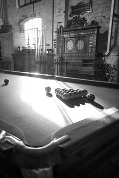 a pool table with several balls on it in front of a clock and other items