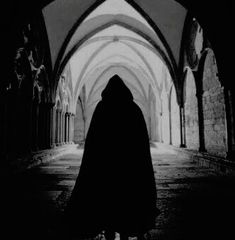 a person in a black cloak is walking through an archway