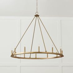 a gold chandelier hanging from the ceiling in a room with white walls and wood flooring