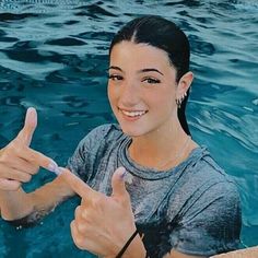 a woman is giving the peace sign in front of a swimming pool with blue water