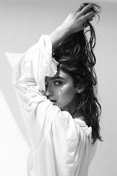 a black and white photo of a woman with her hair blowing in the wind,