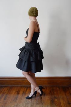 "Description: Black party dress with a drop waist and ruffled skirt. zips up the back and has a large decorative bow. Some tulle under the skirt for fullness. Bodice has boning up the sides. Measurements of garment, allow space for fit. Bust: 32\" some some gathers for cup space. Shown on 36\" and it was way too snug. Waist: 28\" Hips: Open Length: 37\" Skirt length: 15\" I take my measurements flat, and double for circumference. Tag: No brand, just an ILGWU label. Fabric: Polyester Condition: E Party Dress With Ruffle Hem And Tiered Skirt, Party Dress With Ruffle Hem And Fitted Bodice, Party Mini Dress With Bow And Fitted Bodice, Elegant Tiered Skirt Mini Dress For Cocktail, Flirty Tiered Skirt Evening Dress, Elegant Cocktail Mini Dress With Tiered Skirt, Elegant Tiered Mini Dress For Cocktail, Party Mini Dress With Attached Cancan, Formal Fitted Dress With Tiered Skirt