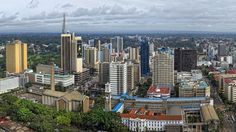 an aerial view of a city with tall buildings in the foreground and trees on the other side