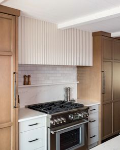 a stove top oven sitting inside of a kitchen next to wooden cabinets and drawers on either side of the wall