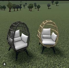 two wicker chairs sitting on top of a green grass covered field next to each other