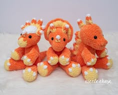 three orange stuffed animals sitting next to each other on a white furnishing surface