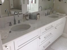 a white bathroom with double sinks and mirrors