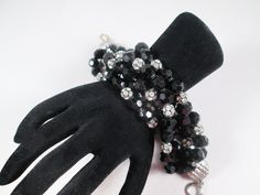 "A spectacular beaded bracelet.  Constructed in six rows of faceted black glass beads with clear rhinestone ball accents, the bracelet is wide, dramatic and oh-so-glamorous.  It's unsigned, most likely dates to the 1980s, with superb quality wiring holding the beads in place.  It's in excellent vintage condition ready to accessorize in 2024! Length 10\" (to accommodate the rows of beads.  Fits my 6.5\" wrist with some room) Width 2\"" Party Multi-strand Faceted Beaded Bracelets, Black Faceted Beads Crystal Bracelet For Party, Black Crystal Bracelet With Round Beads For Party, Black Crystal Bracelet With Faceted Beads For Party, Black Beads Crystal Bracelet For Party, Party Crystal Bracelet With Black Beads, Black Beaded Crystal Bracelet For Party, Black Crystal Bracelet For Party, Black Crystal Party Bracelet