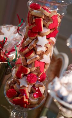 a large glass vase filled with lots of cookies and candies on top of a table