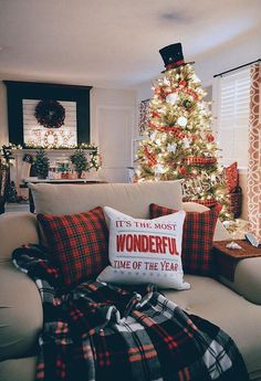 a living room with a christmas tree in the corner and plaid pillows on the couch