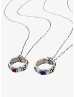 two silver rings with red, blue and white stones hanging from a chain on a white background