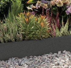 a garden with rocks and flowers in the center, along side it is a black planter filled with plants