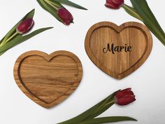 two heart shaped wooden coasters with the word marie engraved on them next to tulips