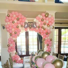 the table is set up for a party with pink, gold and white balloons on it