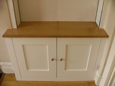 a white cabinet with two doors and a shelf on the top, in front of a doorway