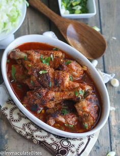 a bowl filled with meat covered in sauce and garnished with fresh parsley