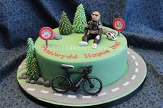 a birthday cake with a cyclist on the road and trees in the backgroud