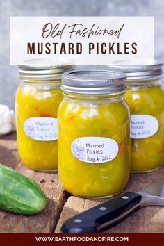 three jars filled with pickles sitting on top of a wooden table next to a knife