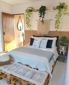 a bed made out of wooden pallets with plants on the wall above it and hanging planters