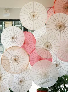 many white and pink umbrellas hanging from the ceiling