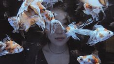 a woman is surrounded by goldfish in an aquarium