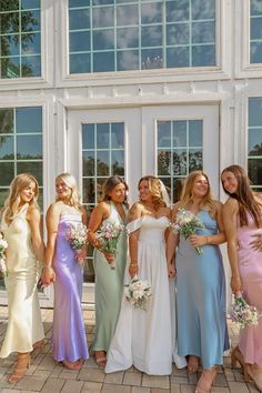 a group of women standing next to each other in front of a large white building