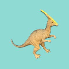 a toy dinosaur with a yellow frisbee in its mouth on a blue background