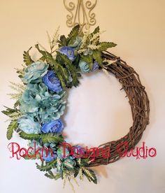 a wreath with blue flowers and greenery hangs on the wall