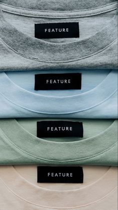 four different colored t - shirts with black labels on them