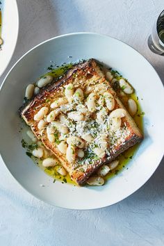 a white plate topped with fish and beans on top of a table next to other dishes