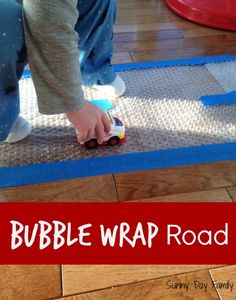 a child is playing with a toy truck on the floor, and it says bubble wrap road