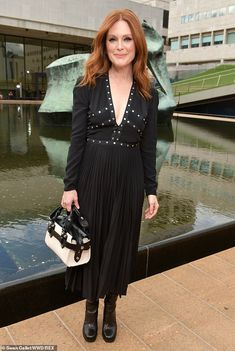 a woman standing in front of a fountain holding a purse