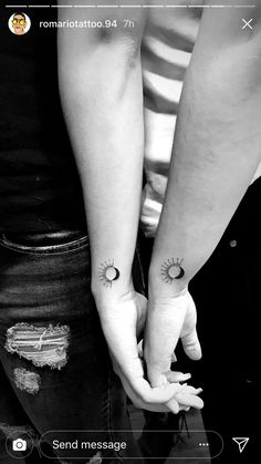 two people are holding hands with tattoos on their arms and one is holding the other's hand