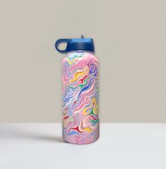 a colorful water bottle with a blue lid on a white table next to a gray wall