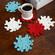 a cup of coffee sitting next to some crocheted snowflakes