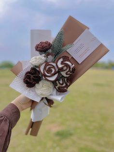 a bouquet of flowers is being held by someone's hand in the grass outside