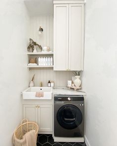 a washer and dryer in a small room with white cabinets on the wall