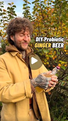 a man holding a beer in his right hand and wearing a yellow jacket with the words diy, probiotic ginger beer on it