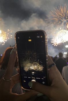 someone holding up their cell phone to take a photo of fireworks