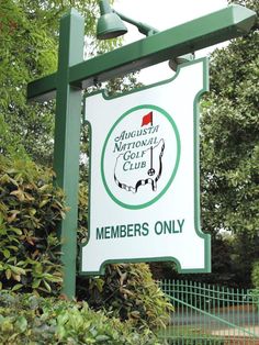 a green and white sign that is on the side of a fenced in area