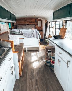 the interior of an rv with wood flooring and white cabinets, including a bed