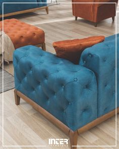 a blue couch sitting on top of a hard wood floor next to two orange chairs