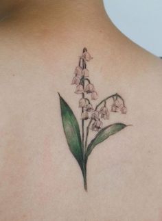 the back of a woman's shoulder with lily of the valley tattoo on it