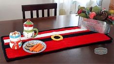 a table topped with a red and black place mat next to a bowl of carrots