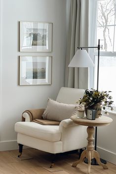 a living room with white furniture and pictures on the wall