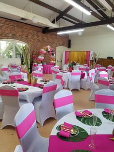 tables and chairs are set up for an event with pink and white linens on them